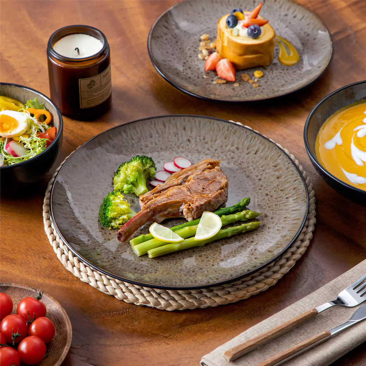 Cozy single-serving brown Bubble 16-piece dinnerware set with plates, bowls, and soup bowls, beautifully styled with pumpkin soup, roasted lamb, pasta, and dessert.