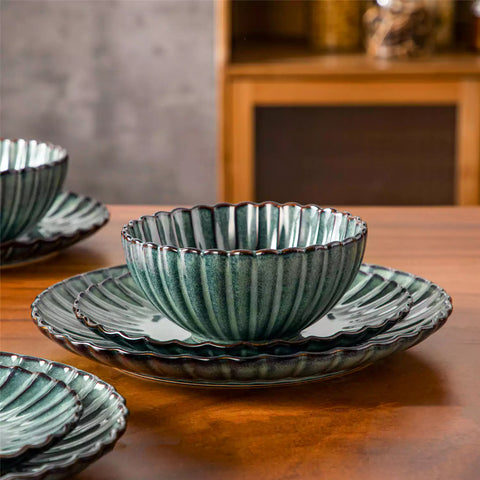 Green reactive glaze stoneware bowls and plates from the Adonis 12 piece set with brown placemats and fresh flowers