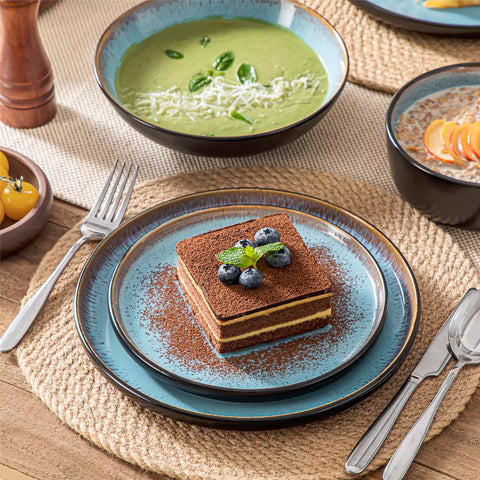 Assorted dishes with soup - dessert - and fruit salad on rustic wooden table - Amber 16-Piece blue stoneware dinnerware set with plates and bowls by vancasso