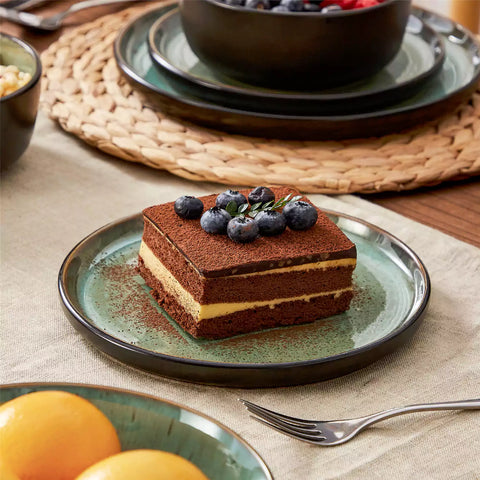 Assorted dishes with soup - dessert - and fruit salad on rustic wooden table - Amber 16-Piece green stoneware dinnerware set with plates and bowls by vancasso