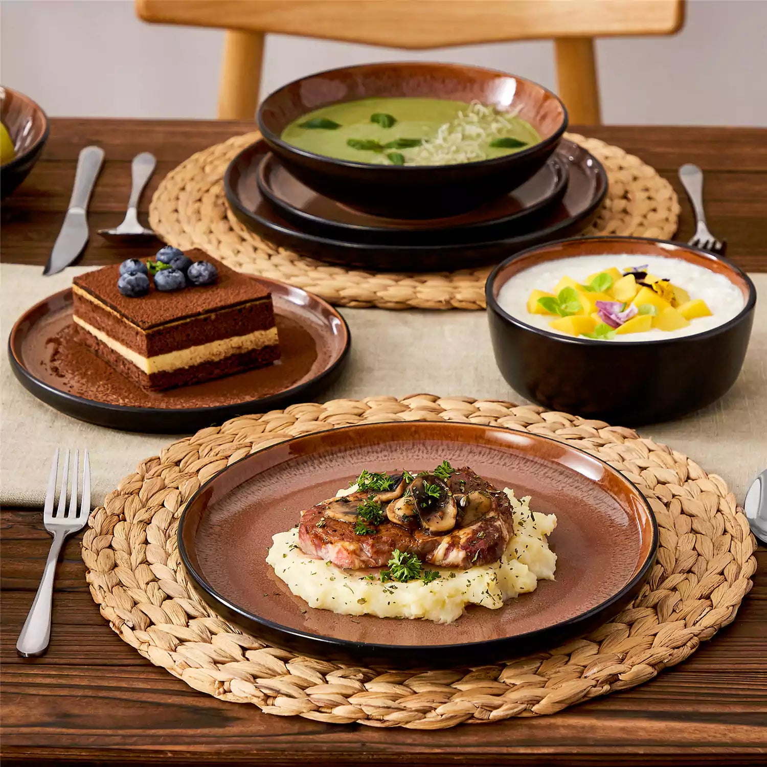 Assorted dishes with soup - dessert - and fruit salad on rustic wooden table - Amber 16-Piece red stoneware dinnerware set with plates and bowls by vancasso