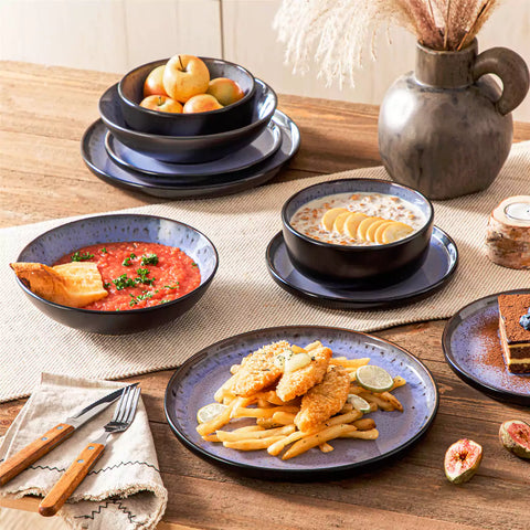 Assorted dishes with soup - dessert - and fruit salad on rustic wooden table - Amber 16-Piece violet stoneware dinnerware set with plates and bowls by vancasso