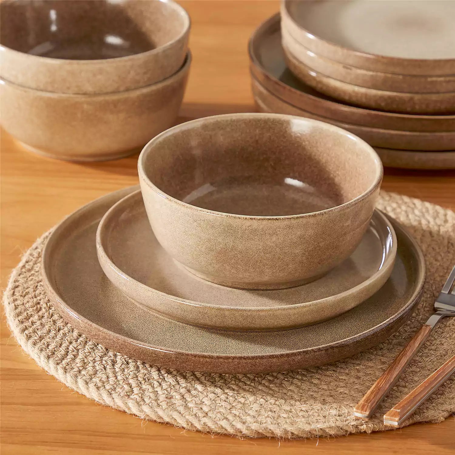 Caramel stoneware plates and bowls with reactive glaze on farmhouse wooden table with woven placemats