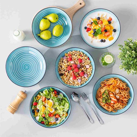 Bonbon double-sided stoneware pasta bowls in blue - artfully filled with pasta - fresh fruit salad - pumpkin soup - and oatmeal - exuding rustic charm on a white dining table