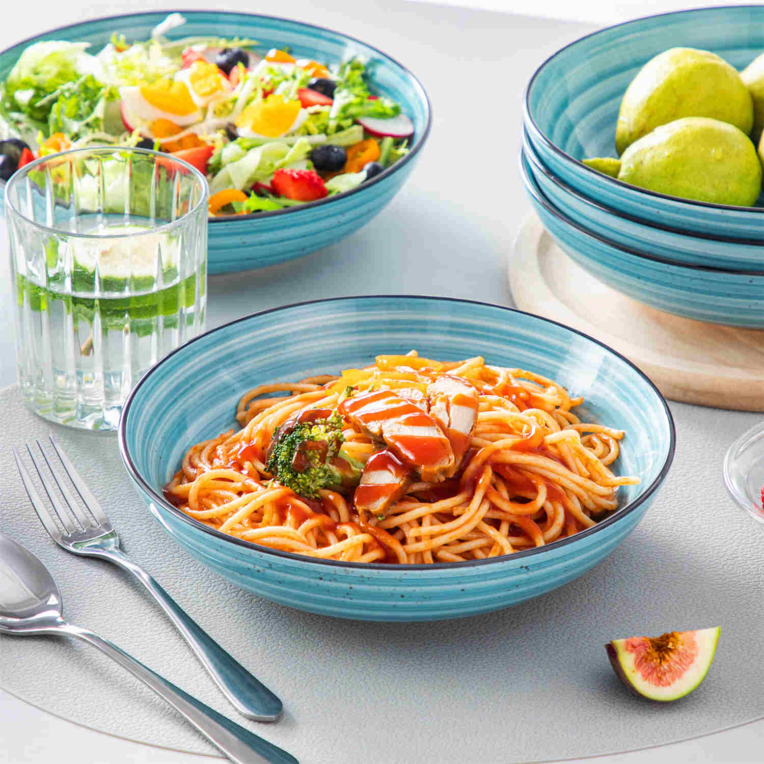 Bonbon double-sided stoneware pasta bowls in blue - artfully filled with pasta - fresh fruit salad - pumpkin soup - and oatmeal - exuding rustic charm on a white dining table