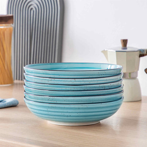 Bonbon double-sided stoneware pasta bowls in blue - artfully filled with pasta - fresh fruit salad - pumpkin soup - and oatmeal - exuding rustic charm on a white dining table