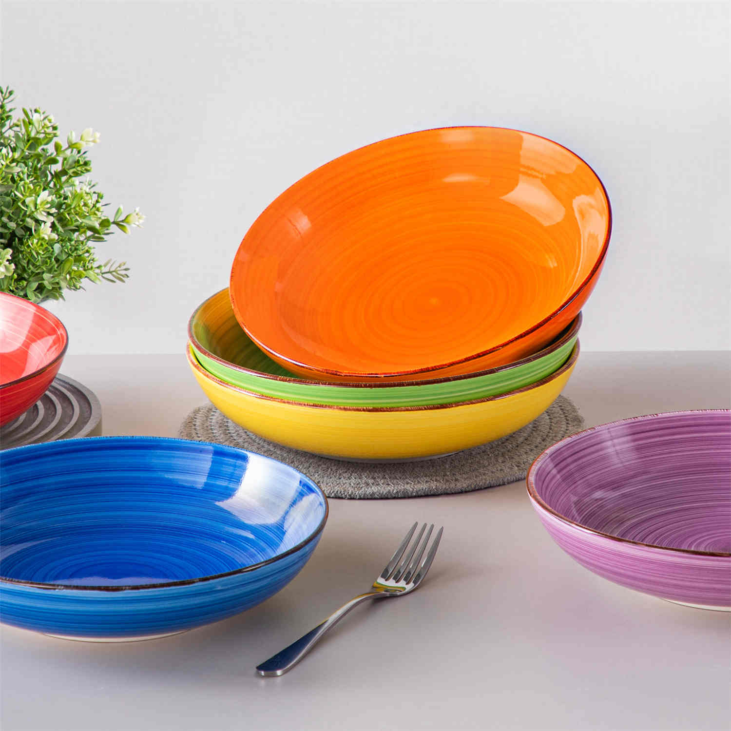 Multicolor Bonita large stoneware bowls set of 6 on a white table - each filled with pasta - pumpkin soup - and fruit salad - creating a bright and inviting table setting