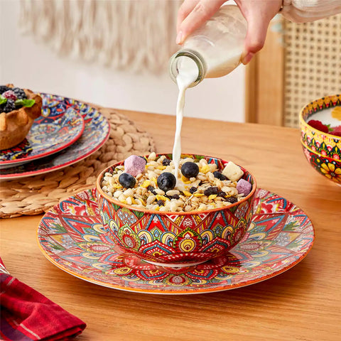 Lumi 12-piece Bohemian dinnerware set for 4 with colorful patterned plates and bowls on a wooden Boho dining table with food