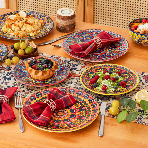 Lumi 18-piece Bohemian dinnerware set for six on a wooden table with colorful plates bowls and silverware in a playful Boho style