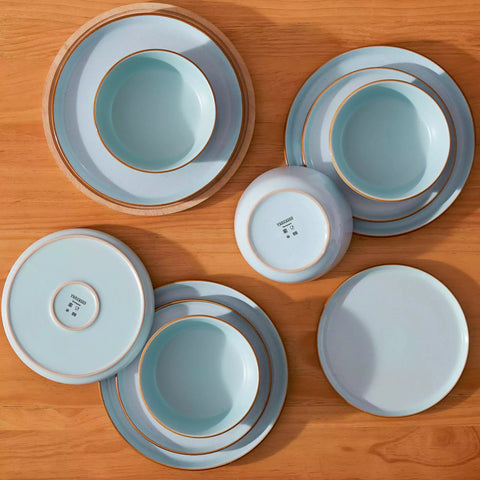 Blue rustic stoneware dinnerware set with speckled - lipped-edge plates and bowls on a dining table with flowers and cutlery in a cozy modern kitchen-vancasso