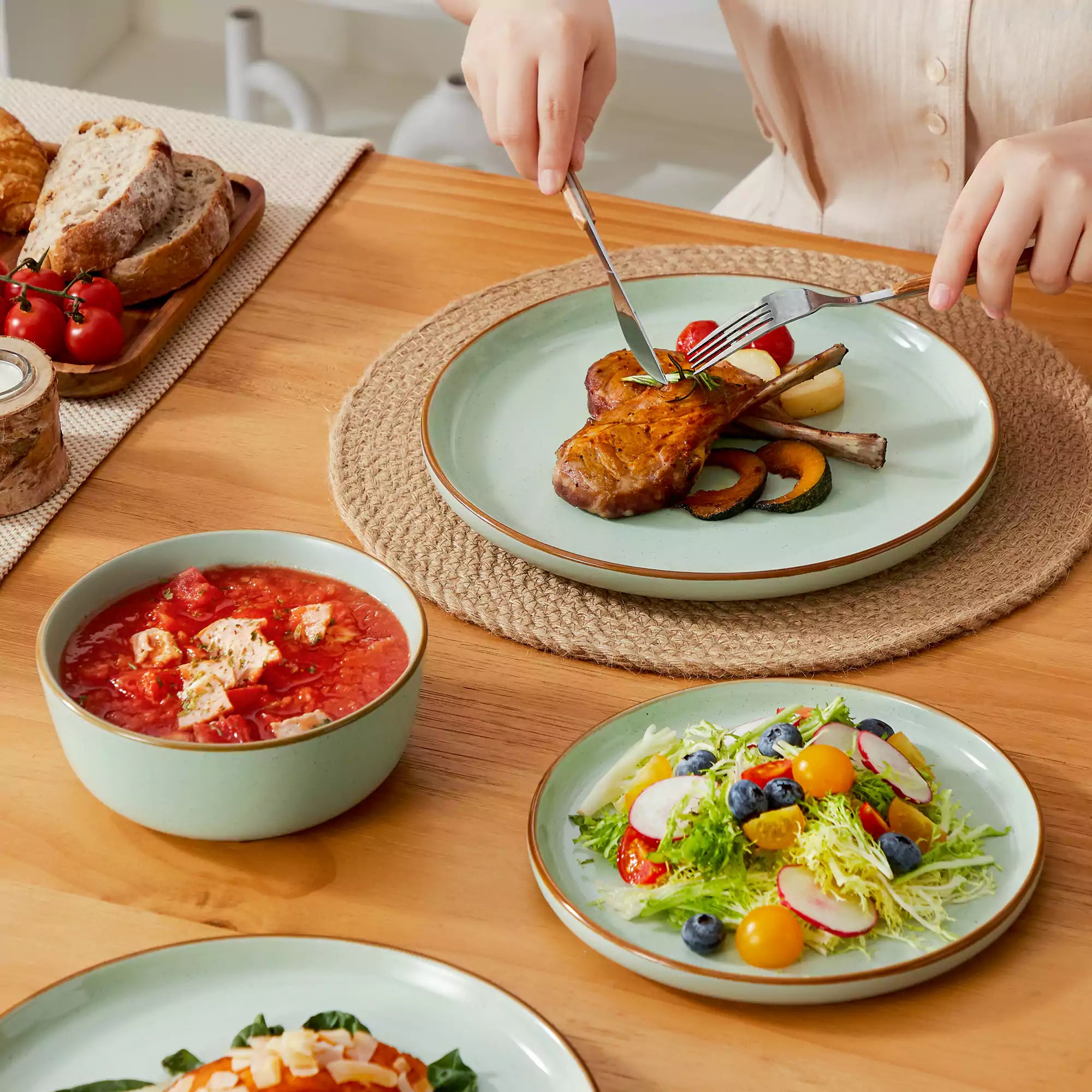 Green rustic stoneware dinnerware set with speckled - lipped-edge plates and bowls on a dining table with flowers and cutlery in a cozy modern kitchen-vancasso