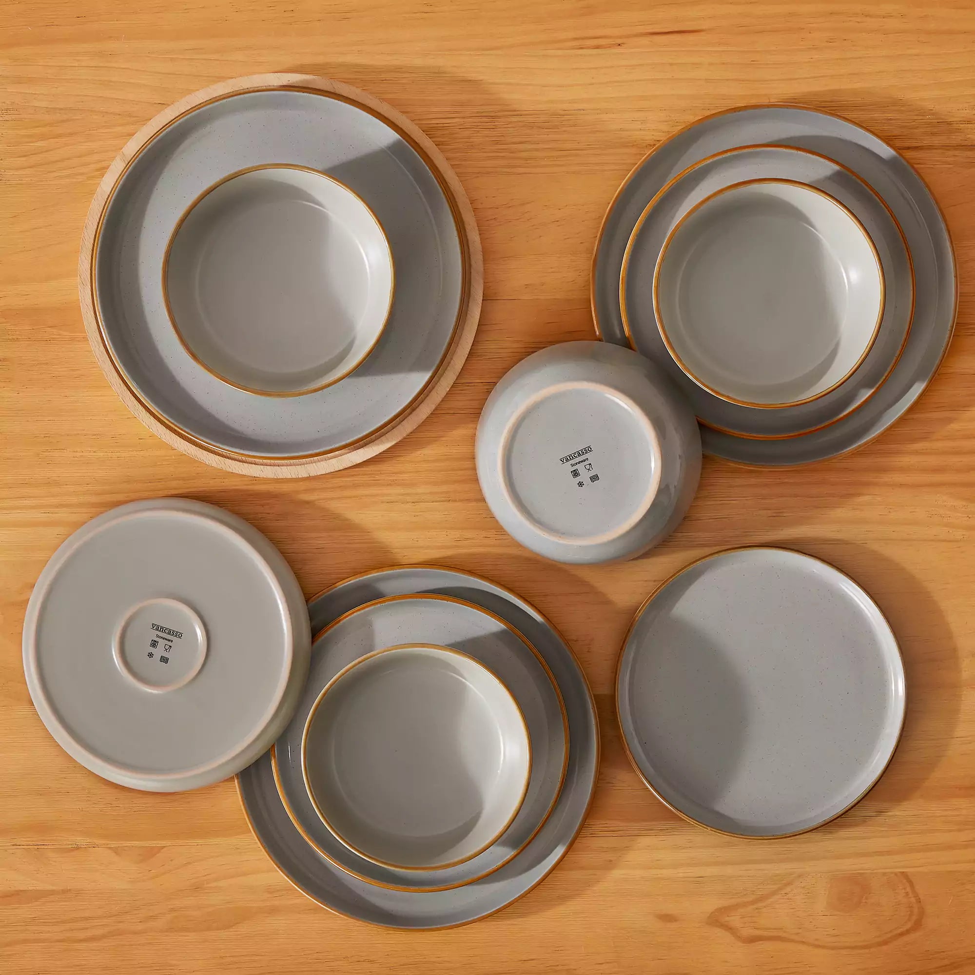 Grey rustic stoneware dinnerware set with speckled - lipped-edge plates and bowls on a dining table with flowers and cutlery in a cozy modern kitchen-vancasso