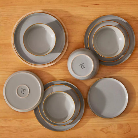 Grey rustic stoneware dinnerware set with speckled - lipped-edge plates and bowls on a dining table with flowers and cutlery in a cozy modern kitchen-vancasso