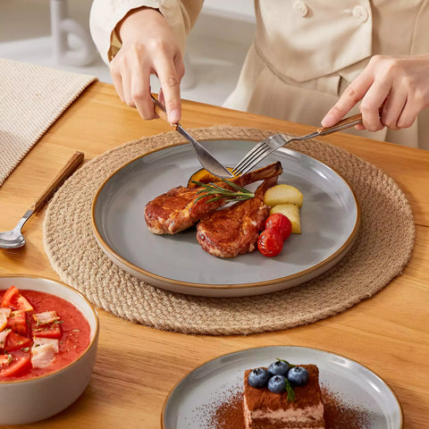 Grey rustic stoneware dinnerware set with speckled - lipped-edge plates and bowls on a dining table with flowers and cutlery in a cozy modern kitchen-vancasso