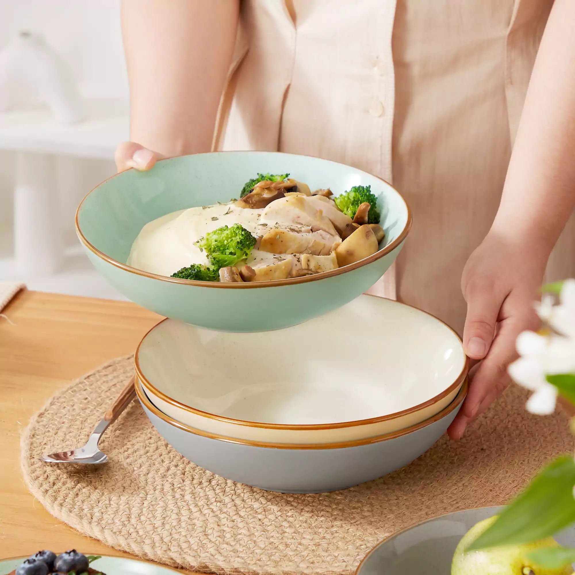 Rustic assorted speckled stoneware dinnerware set with lipped-edge plates and bowls arranged on a sunlit modern dining table-vancasso