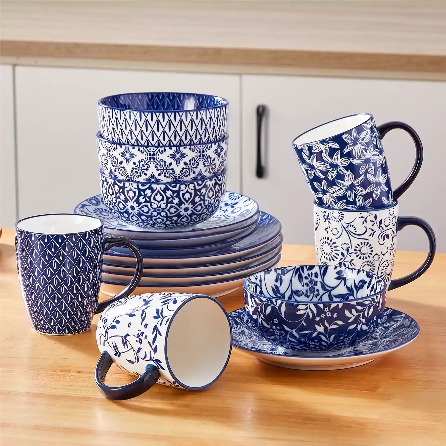 Selene 16-piece porcelain set in indigo patterns - showcasing plates - bowls - and mugs beautifully styled with vibrant meals on a rustic wooden table