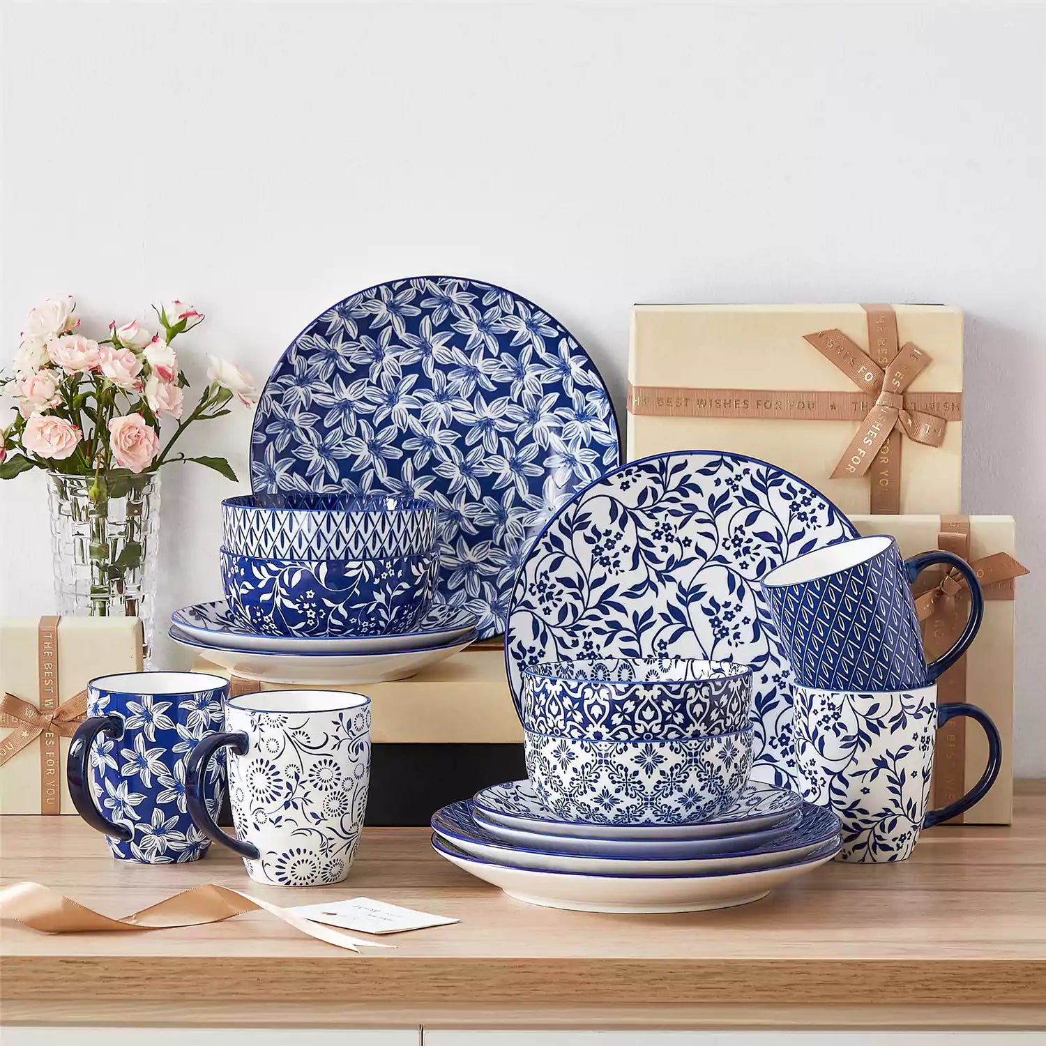 Selene 16-piece porcelain set in indigo patterns - showcasing plates - bowls - and mugs beautifully styled with vibrant meals on a rustic wooden table