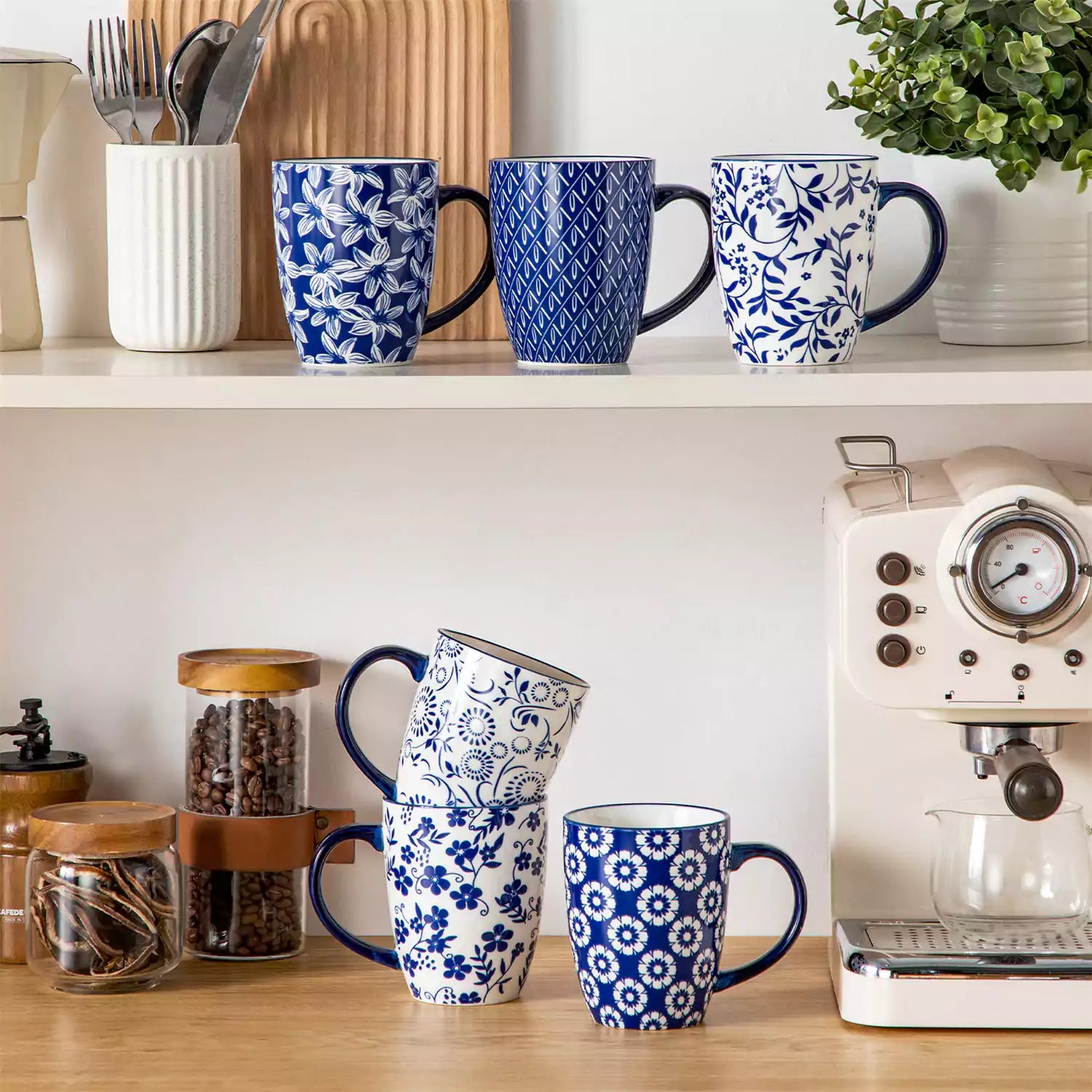 Set of six Japanese-style stoneware mugs in blue and white with indigo patterns, displayed on a kitchen counter with scattered coffee beans