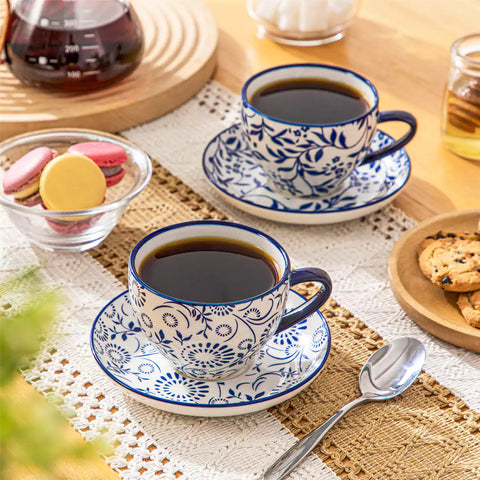 Set of 4 Selene indigo floral porcelain cups and saucers on a wooden table with coffee and pastries featuring blue and white Japanese style mix and match patterns