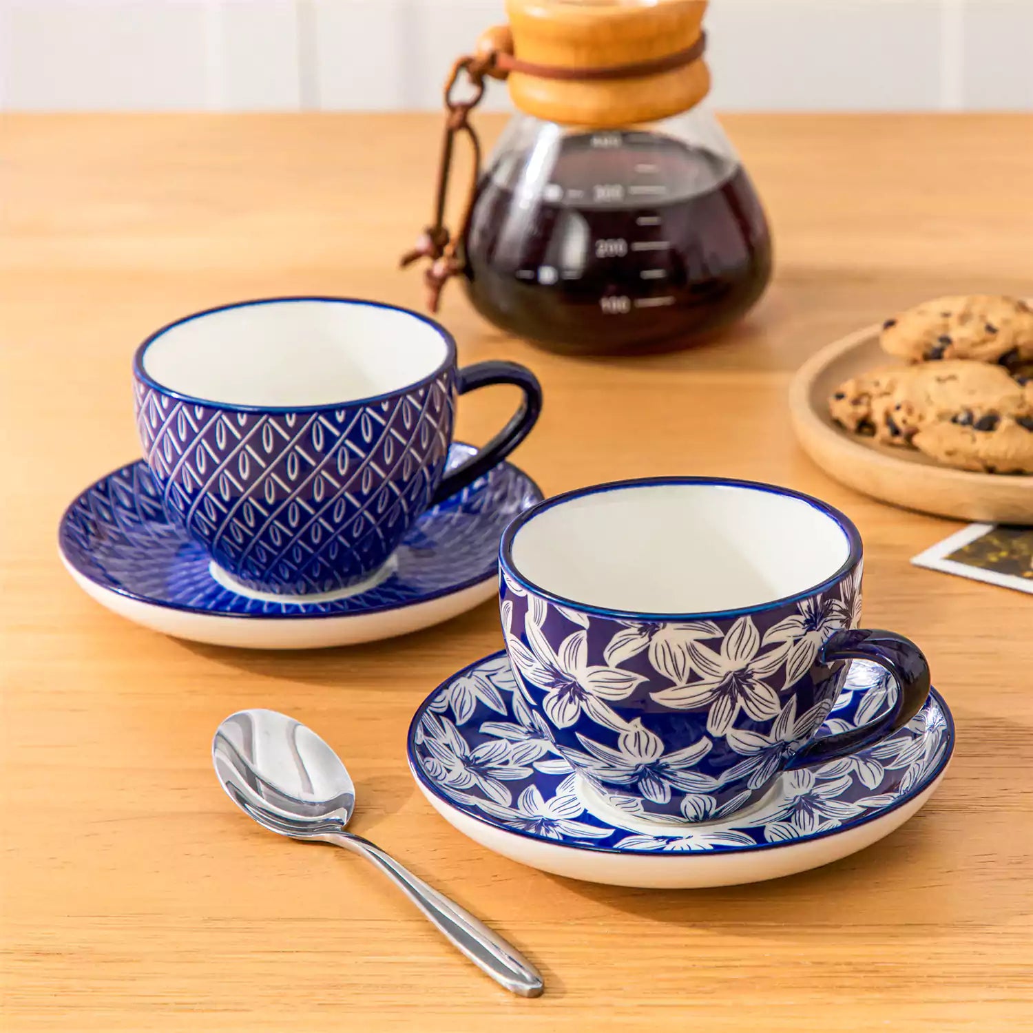 Set of 4 Selene indigo floral porcelain cups and saucers on a wooden table with coffee and pastries featuring blue and white Japanese style mix and match patterns