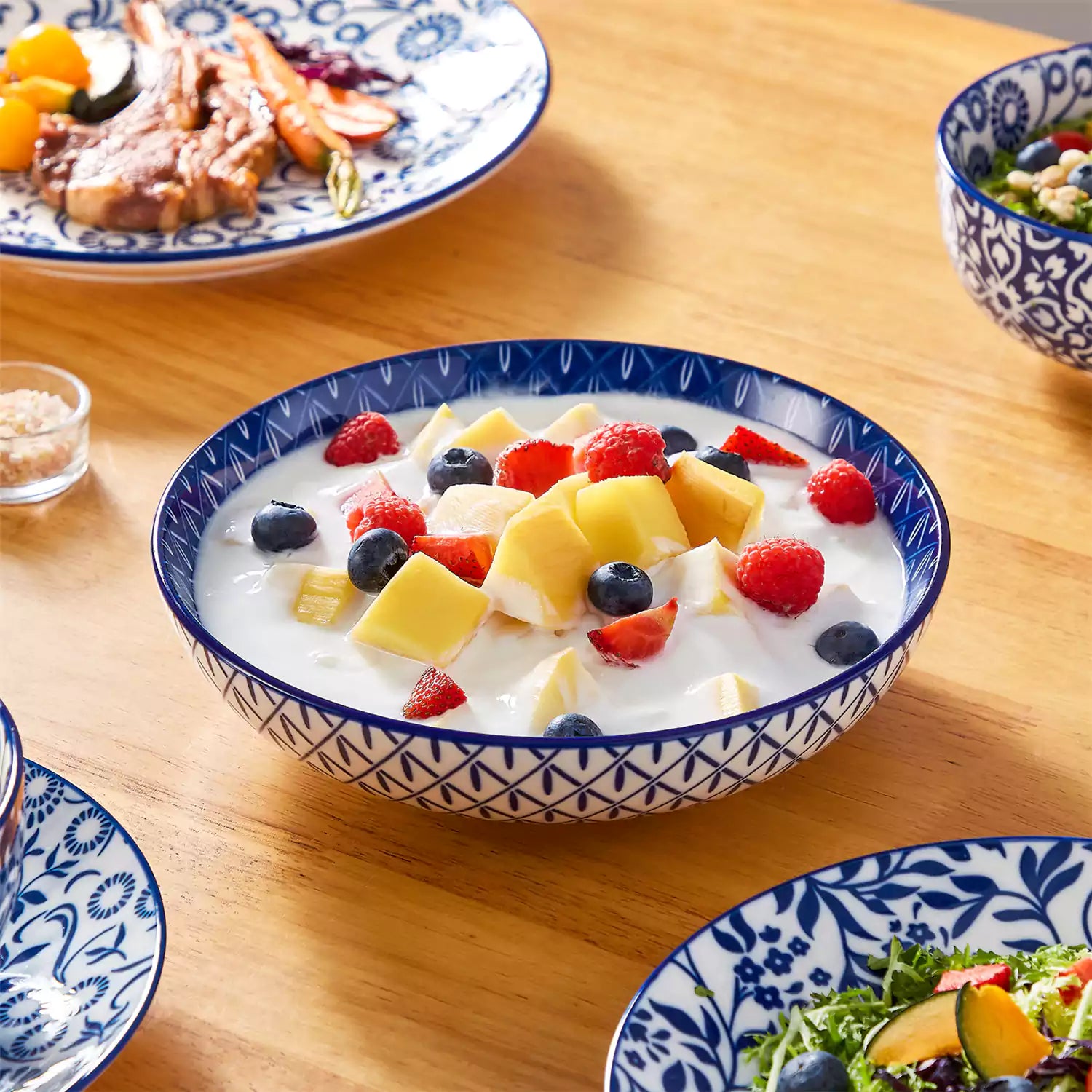 Selene 16-piece porcelain set with indigo floral and geometric patterns on plates - bowls - and mugs displayed on a dining table