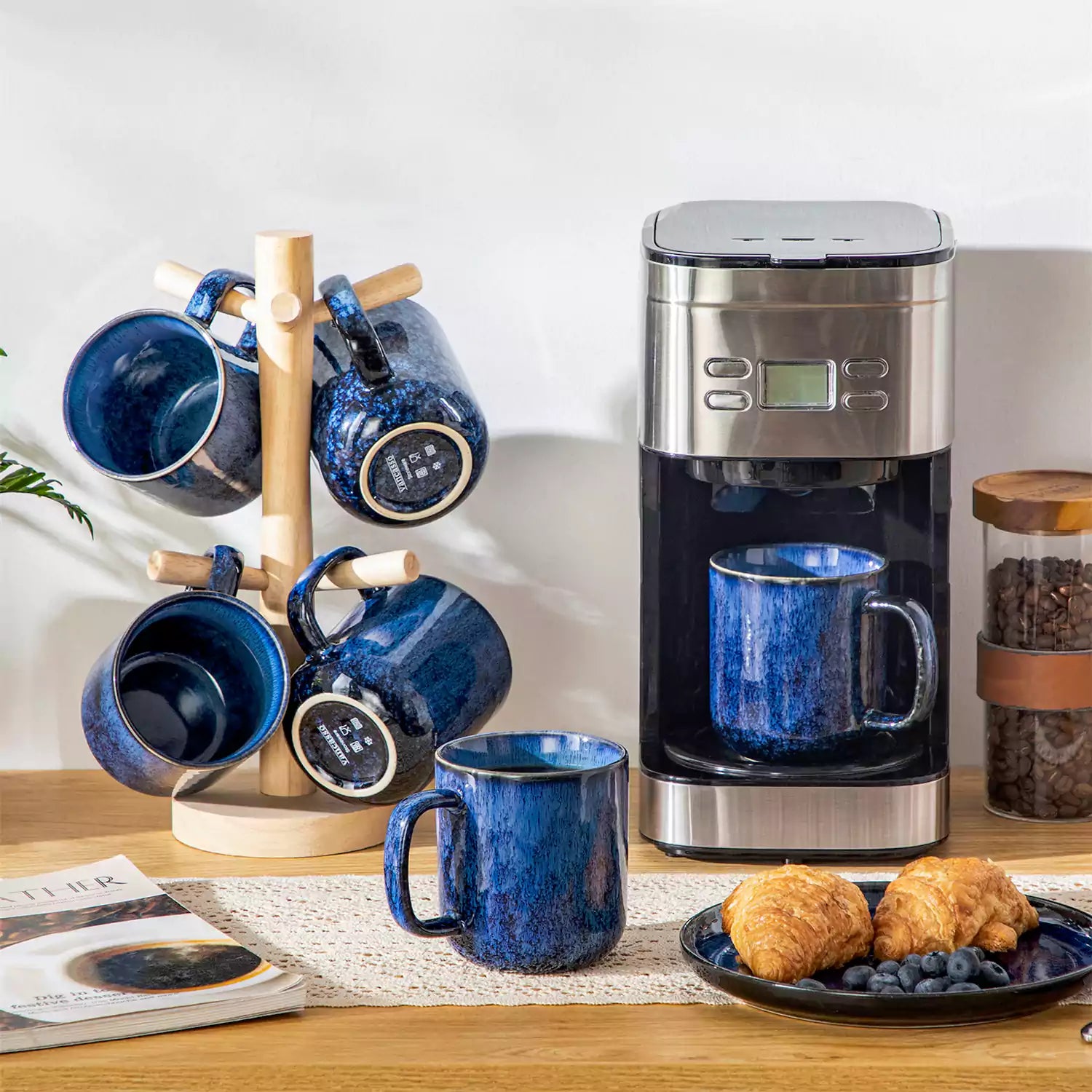 Starry gently curved blue mugs set of 6 displayed on a wooden table with a coffee maker and a plate of pastries