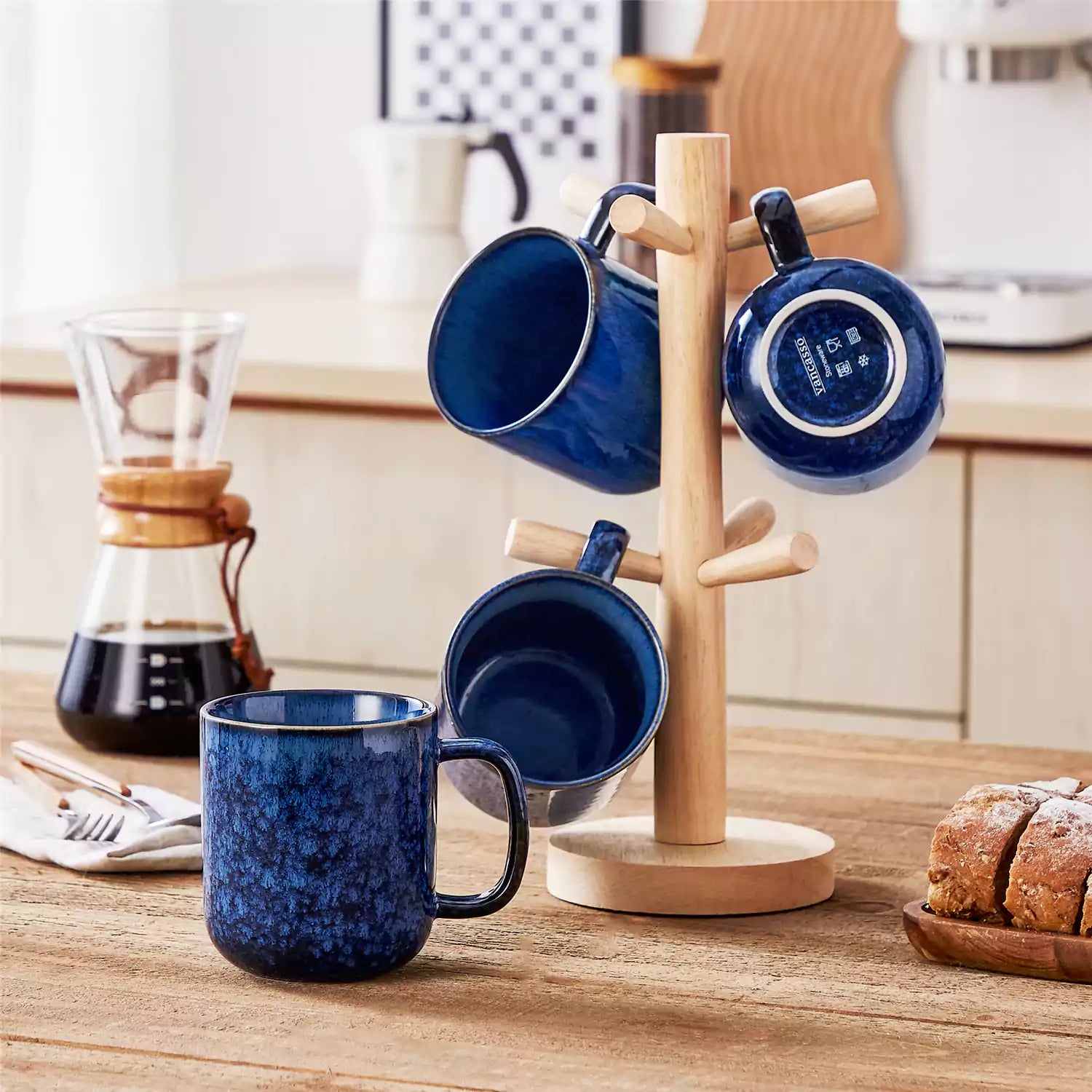 Four starry blue 16oz stoneware mugs with latte art on wooden table beside coffee brewing equipment
