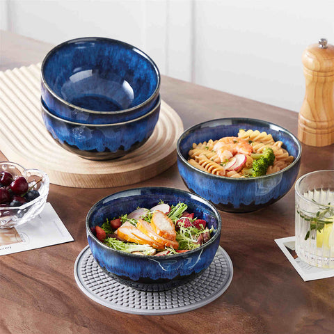 Starry reactive glaze cereal bowls in blue on a rustic wooden table - filled with creamy soup - pasta - and fresh fruit salad for a cozy - celestial dining vibe