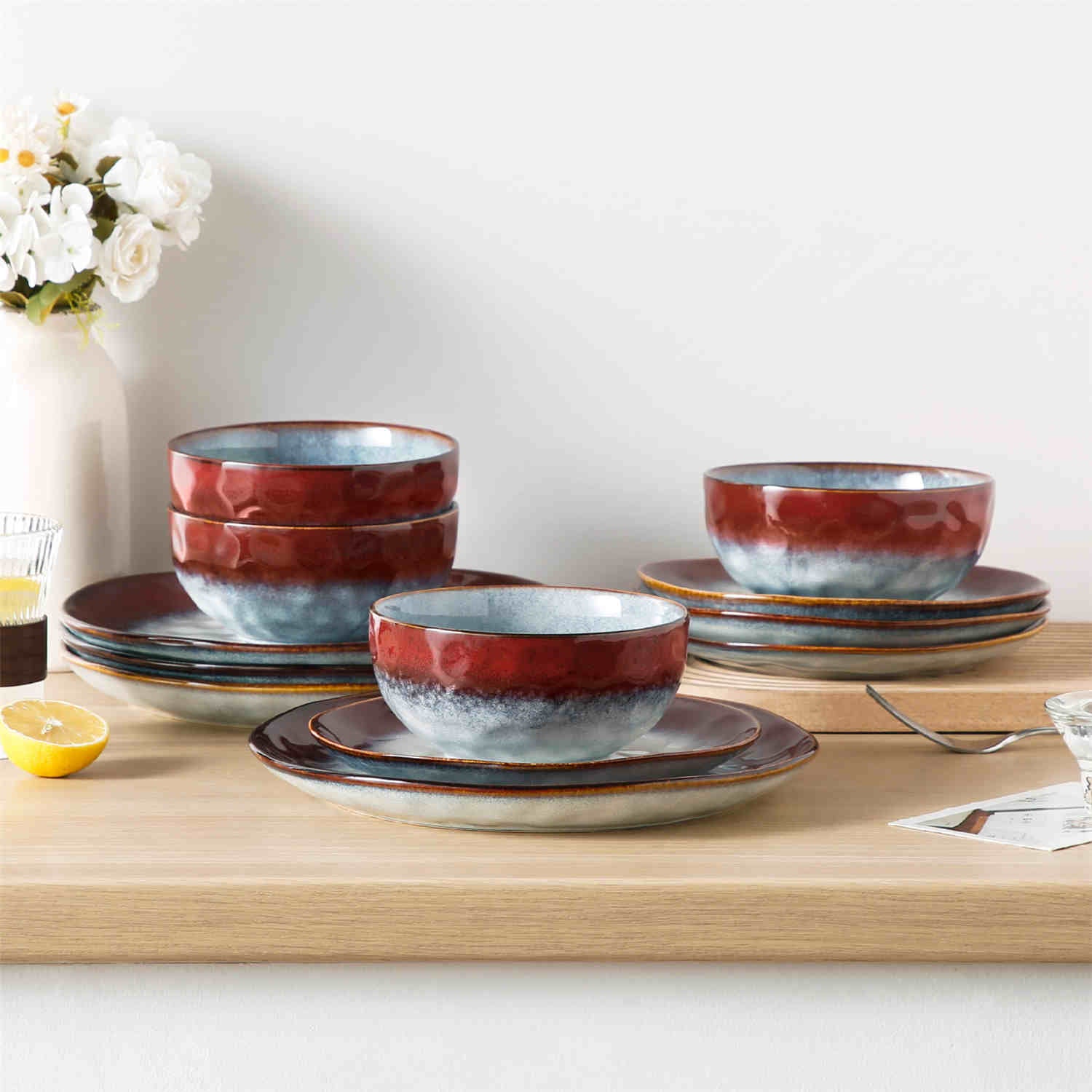 Starry 12-piece stoneware dinnerware set in red on a light wooden table - styled with lamb chops - pastries - coffee pot - and lemon water for a cozy farmhouse breakfast scene