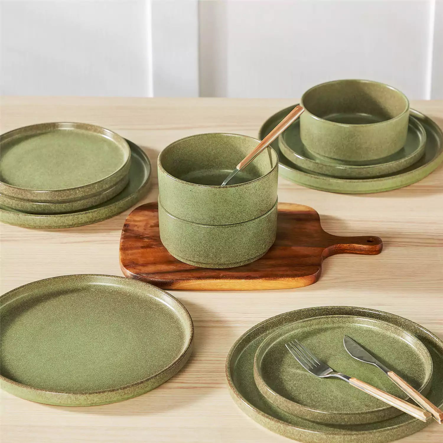 Green reactive glaze stoneware dinner plates styled with food on rustic wood table with woven placemats modern minimalist tableware set